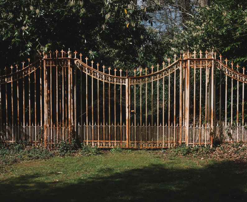 Decorative wrought iron gate framed by green trees